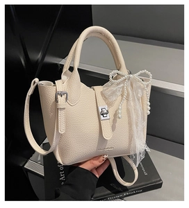 Detail of beige lychee leather bucket bag with pearl bow charm and silver lock