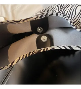 Detail of zebra pattern fabric bag with black leather tab and silver magnetic closure