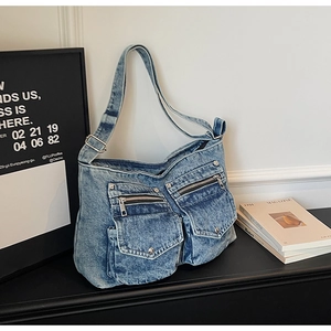Detail of blue denim tote bag with silver zippers and pockets on a stylish background