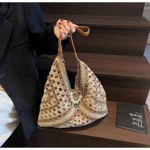 Detail view of a woven checkered tote bag with pearl chain and leather handles