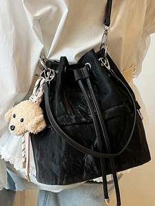 Chic black drawstring bucket bag with wavy texture and cute dog pendant accessory