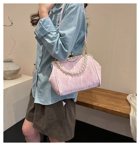 Detail of pink pleated shell bag featuring pearl bead handle and gold metal clasp