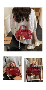 Detail of wine red glossy leather handbag featuring decorative straps and a horse charm