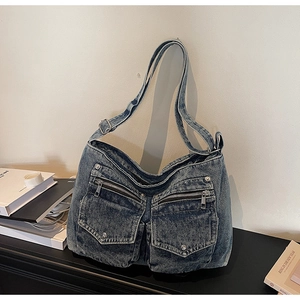Detailed macro view of vintage wash denim shoulder bag with silver metal rivets and pockets