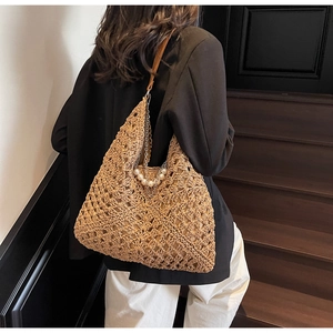 Detail of hand-woven hollow straw tote bag with elegant pearl chain and leather shoulder strap