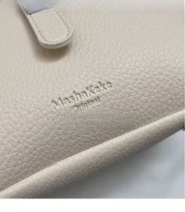 Close-up detail of beige pebble leather bucket bag with embossed logo texture
