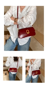 Detailed macro view of dark red leather shoulder bag featuring gold rectangular clasp buckle