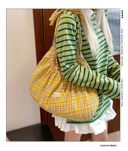 Close-up of vibrant yellow plaid tote bag with stylish pleated fabric and brand logo