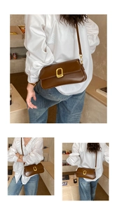 Close-up of a brown leather crossbody bag featuring a classic gold rectangular buckle