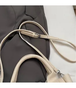 Detail of adjustable leather strap and top handle on a solid color bucket bag