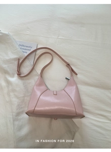 Detail view of pink leather hobo bag with a metallic buckle on white textured fabric