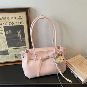 Close-up of pink faux leather tote bag featuring a decorative buckle and plush puppy charm