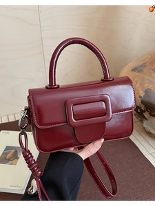 Detailed macro view of burgundy polished leather texture and large buckle on handbags