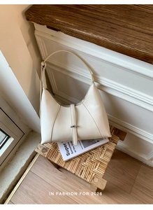 Detail view of cream white crescent hobo bag with sleek leather finish and belt buckle accent
