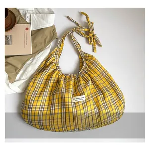 Detail view of yellow plaid tote bag with large ribbon knot strap and brand label