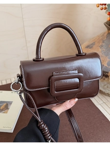 Macro detail of glossy dark brown PU leather handbag with elegant buckle and texture