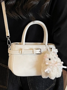 Minimalist white leather crossbody bag with decorative buckle and plush bunny charm
