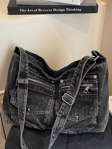 Washed black denim tote bag with multiple pockets and silver hardware on a shelf