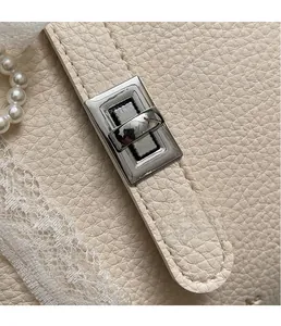 Close-up of elegant silver rotating lock and textured lychee leather on bucket bag