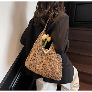 Detail of hand-woven hobo straw bag with pearl accents and leather shoulder strap