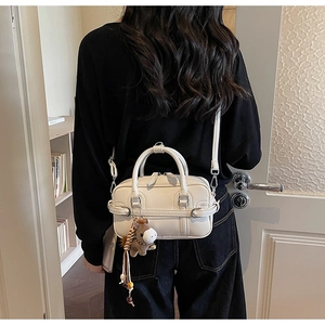 Detail of elegant cream leather handbag with cute brown horse plush charm accessory