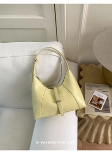Detailed view of cream-colored crescent hobo bag with sleek leather finish and buckle strap