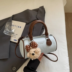 Detail of light blue Boston bag with brown handles and a cute teddy bear charm