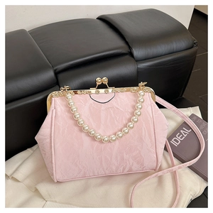 Close-up of pink pleated shell bag featuring vintage gold floral clasp and pearl handle