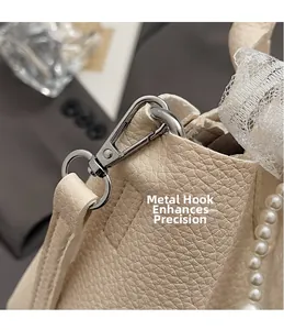 Detail of silver hardware hook and pearl chain on creamy white lychee leather bucket bag