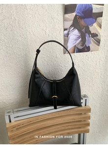 Close-up of black leather crescent bag with gold hardware and adjustable strap detail