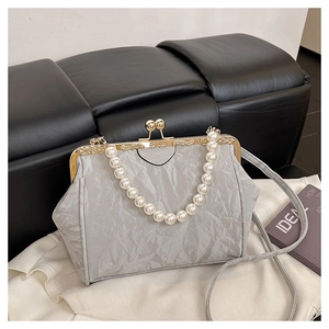 Detailed view of silver pleated clutch bag with large pearl handle and vintage metal clasp