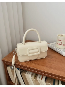 Detail of minimalist beige handbag with large square buckle and woven rope ornament