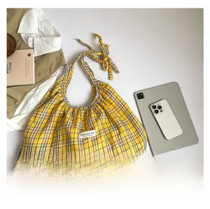 Detail of yellow checkered canvas tote bag with adjustable tie straps and fabric label