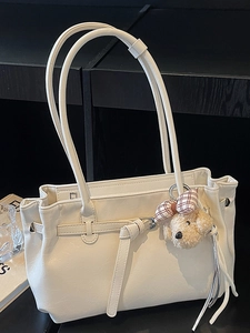 Minimalist beige tote bag with natural leather texture and cute plush bear charm