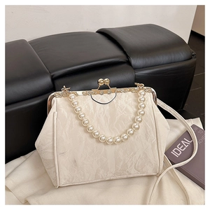 Detail of beaded pearl handle on retro shell bag with cream pleated fabric and gold clasp