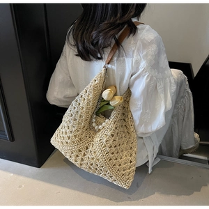 Detail of handwoven hollow pattern on off-white straw tote bag with pearl strap