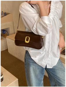 Detail of vintage brown shoulder bag showing the gold buckle and smooth leather texture