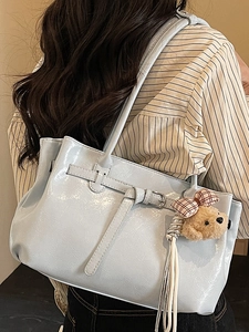 Light blue pleated tote bag with plush bear charm shown on a shoulder in daily use