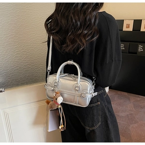Detail of silver metallic bowling bag with detachable strap and brown pony charm on model