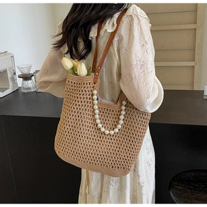 Detailed shot of handmade straw tote bag with elegant large pearl chain and leather strap
