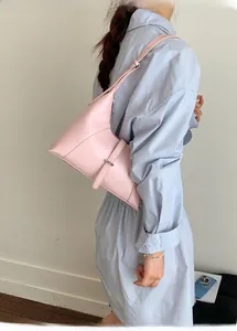 Detailed view of pink asymmetric crescent bag with silver buckle worn over the shoulder
