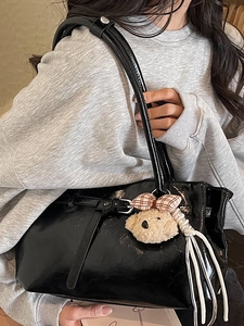 Glossy black patent leather tote bag with shoulder straps and plush bear charm