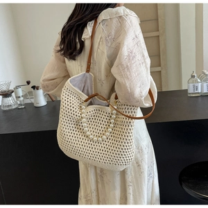 Detail of handmade woven tote bag featuring pearl chain strap and brown leather handles