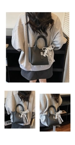 Detail of black pebbled leather bucket bag with silver buckle and pearl bow charm