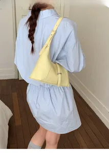 Detail of light yellow hobo bag with adjustable strap and metal hardware on model