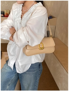 Close-up of beige baguette bag with elegant gold rectangular buckle and smooth texture