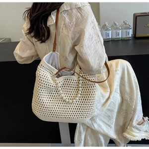 Detail of hand-woven off-white tote bag featuring pearl handles and leather straps
