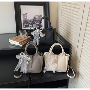 Close-up of three textured bucket bags featuring lace bows and pearl charms in a cozy setting