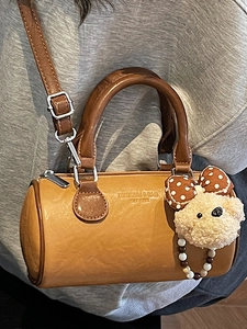 Vintage brown leather cylinder bag with bear charm and adjustable shoulder strap