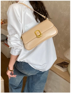 Detail of minimalist beige leather crossbody bag with elegant gold buckle on a model